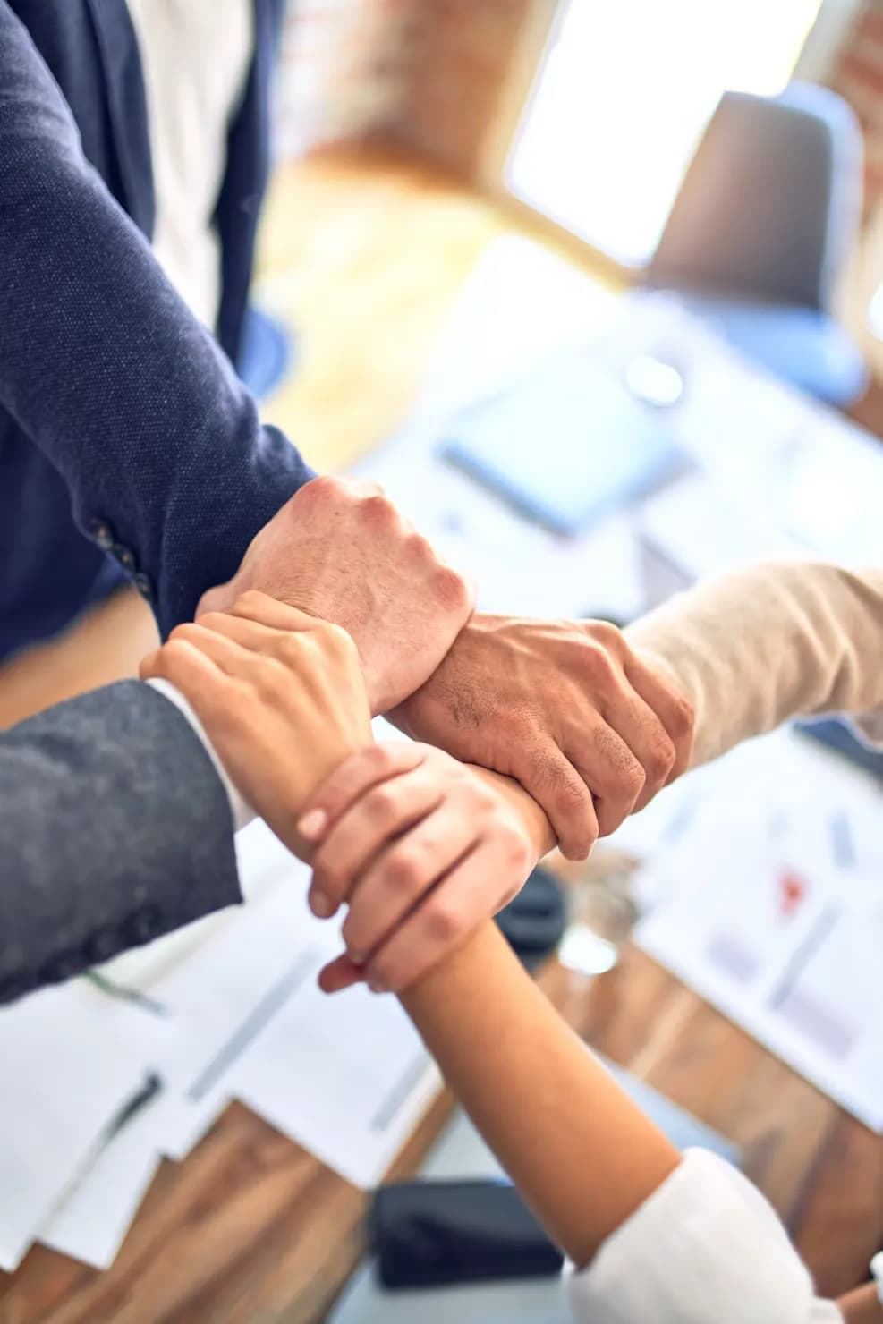 Hands meeting over a desk at a shift handover.