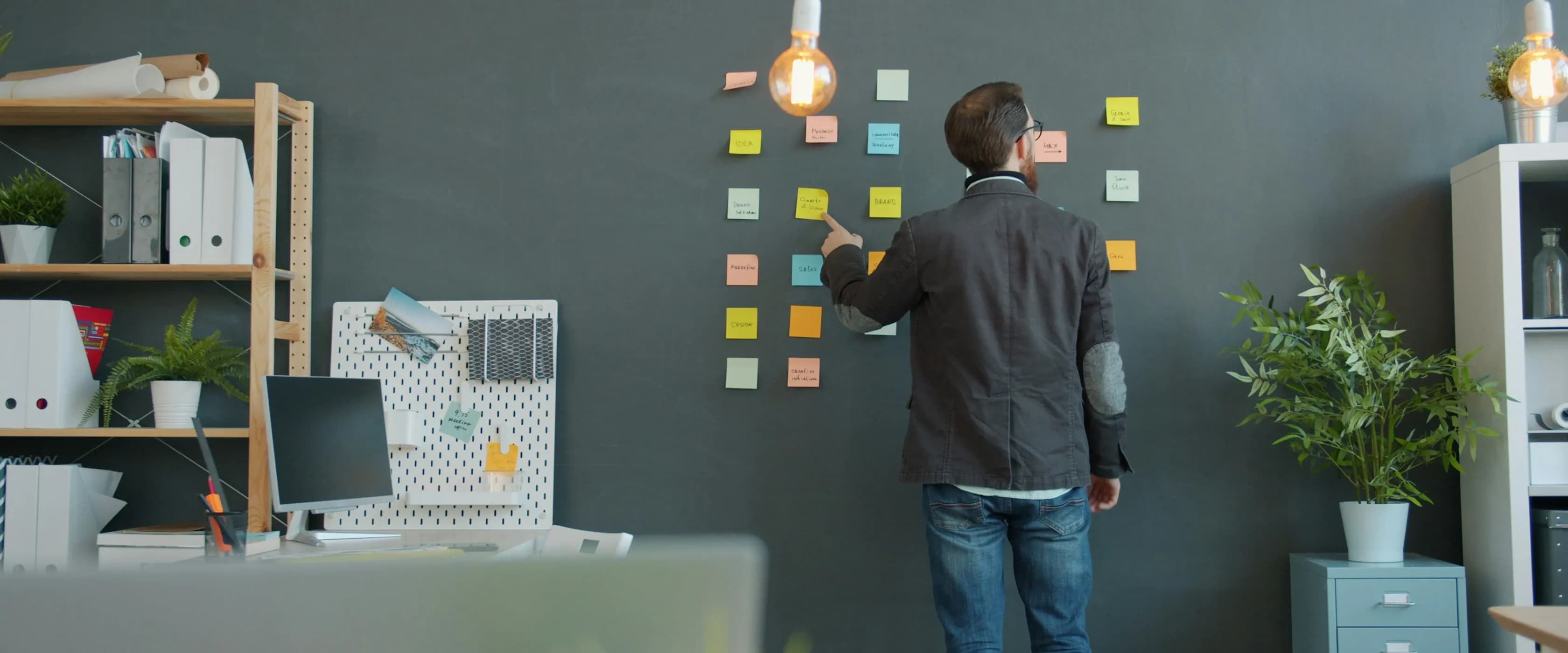 A ClockAide team member standing at a wall of sticky notes in an office, mapping out a workflow.